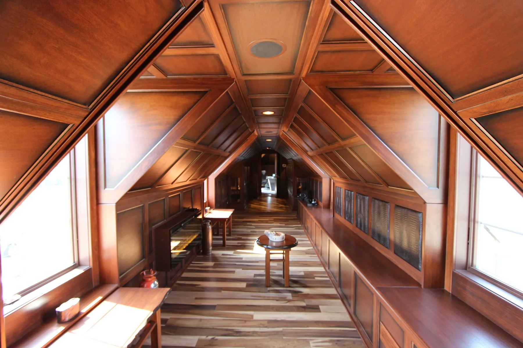 A long attic hallway finished in mahogany and Lyptus with a coffered vaulted ceiling and paneled walls.